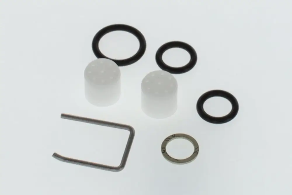 BOSCH Schalldämpfer-Zubehörset mit zwei weißen Zylindern, mehreren schwarzen O-Ringen und einem Metallclip. Teile auf hellem Hintergrund angeordnet.